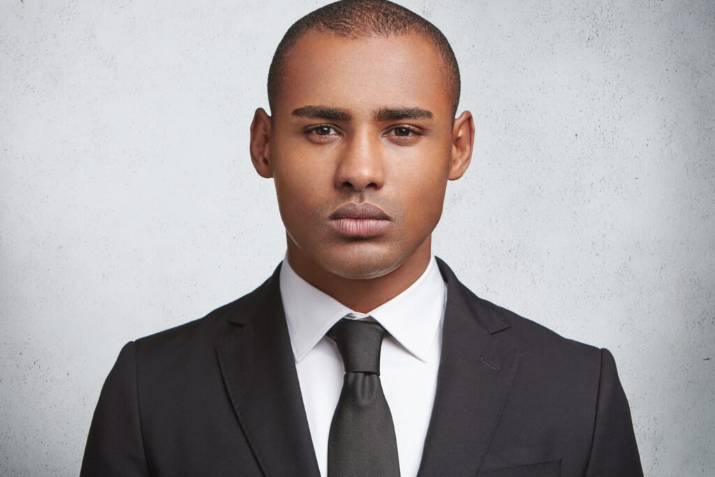 serious male executive director or enterpreneur wears tie and black elegant suit, going to have business meeting with partners, has good partneship, poses against blank white studio background.