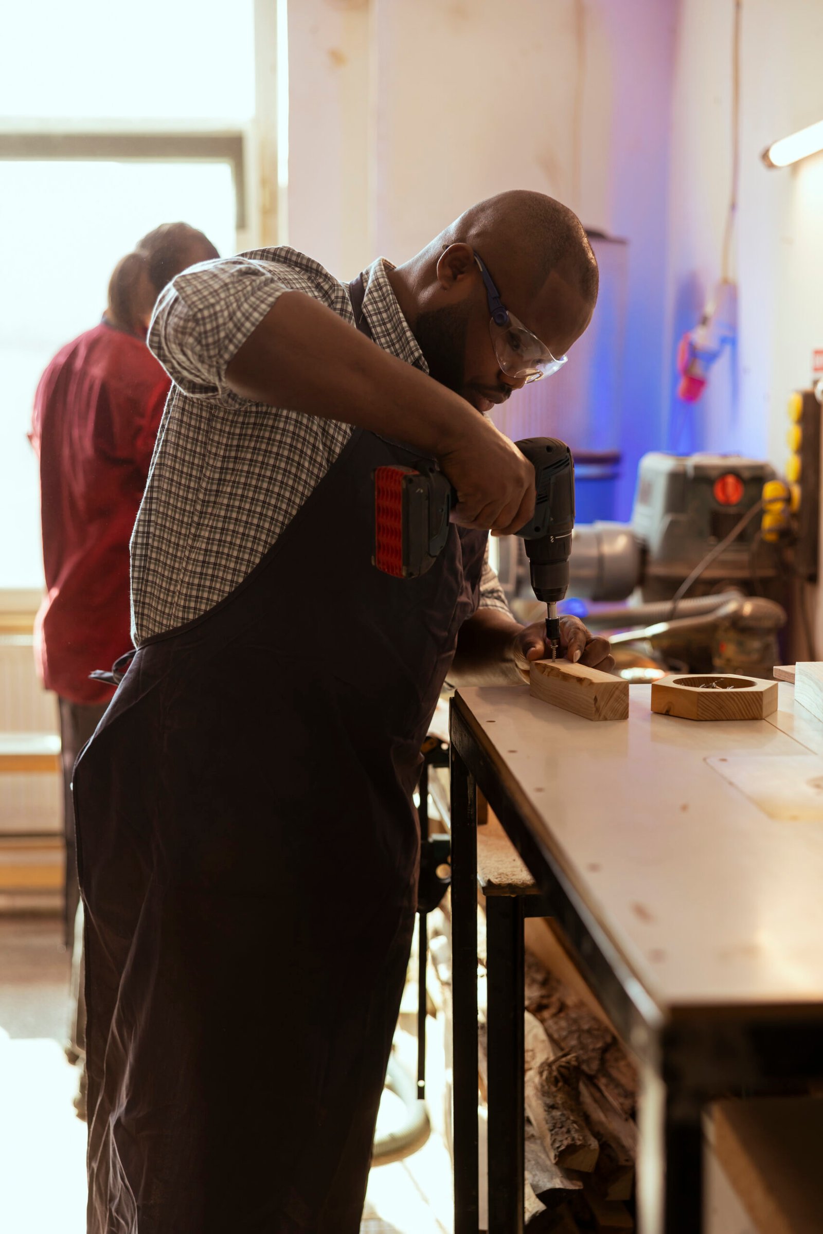 woodworking specialist inserting nail into piece of wood using electric power drill